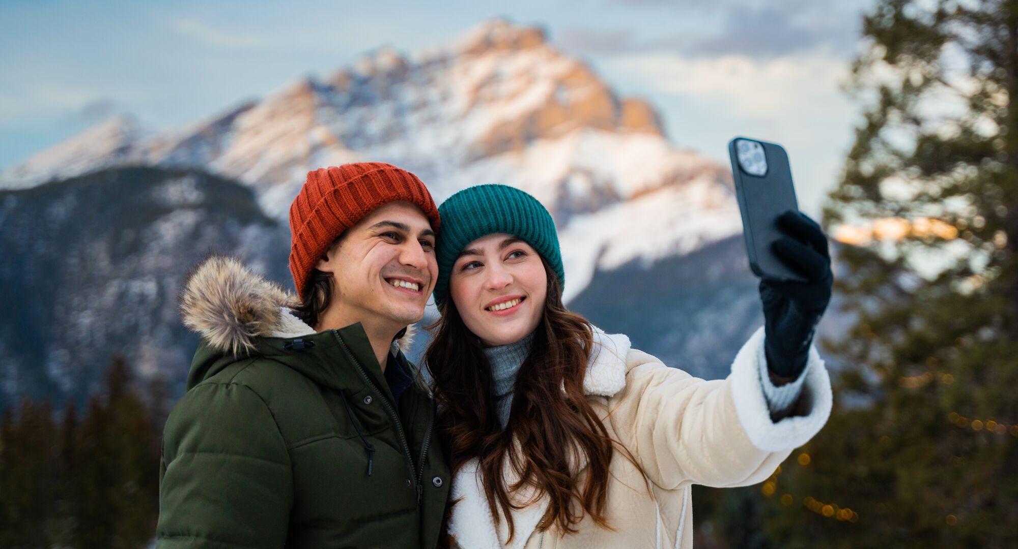 A couple takes a selfie together with Cascade Mountain in the background. 